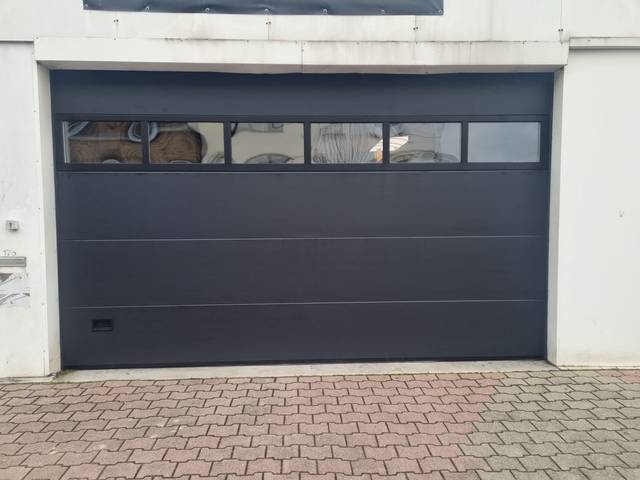 Porte de garage sectionnelle anthracite avec hublots, installation Fermotek
