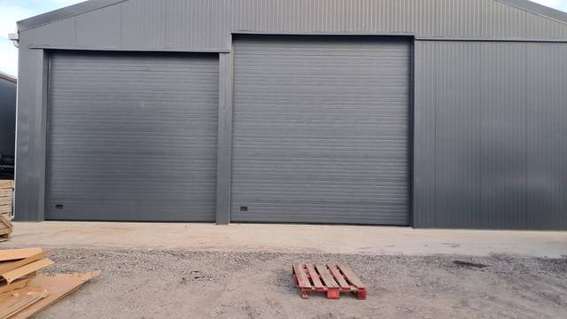 Rideau métallique vert foncé installé sur bâtiment bois, Fermotek